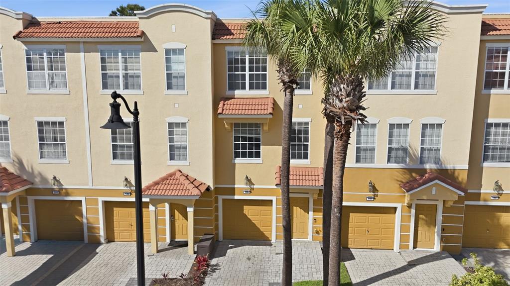 An exterior view of a multi-story townhouse complex with tan stucco walls and tile roofs — 4845 TIDECREST AVENUE UNIT 146, ORLANDO, FL