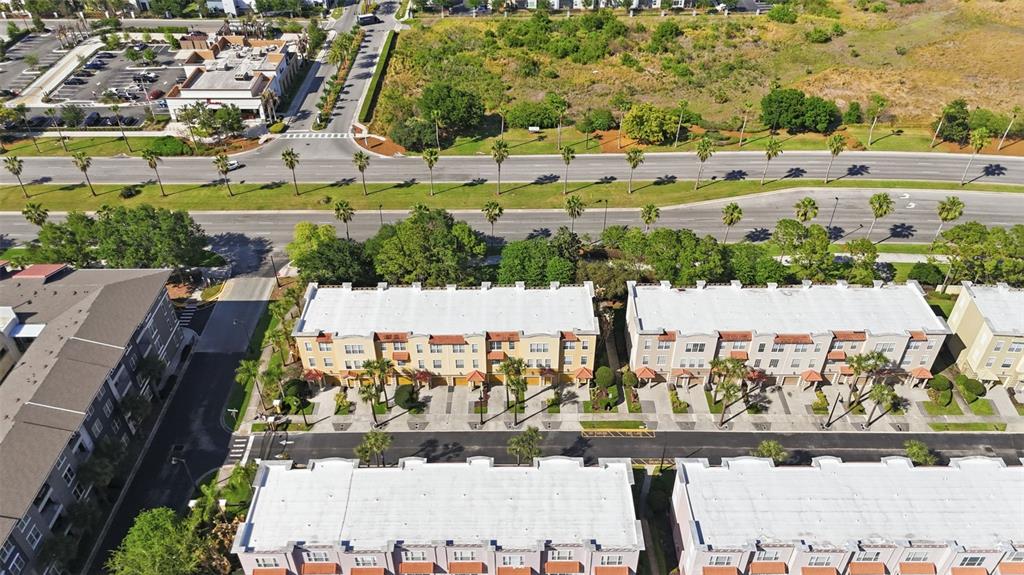 An aerial view shows several multi-story townhome buildings with white roofs and adjacent parking lots — 4845 TIDECREST AVENUE UNIT 146, ORLANDO, FL