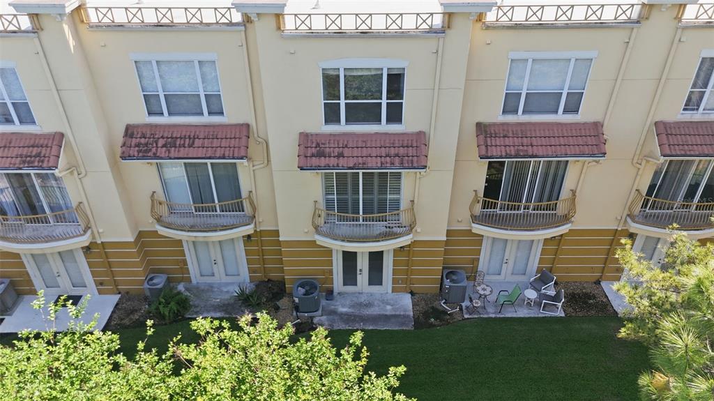 An exterior view of a multi-story townhouse complex with balconies and ground-level patios — 4845 TIDECREST AVENUE UNIT 146, ORLANDO, FL