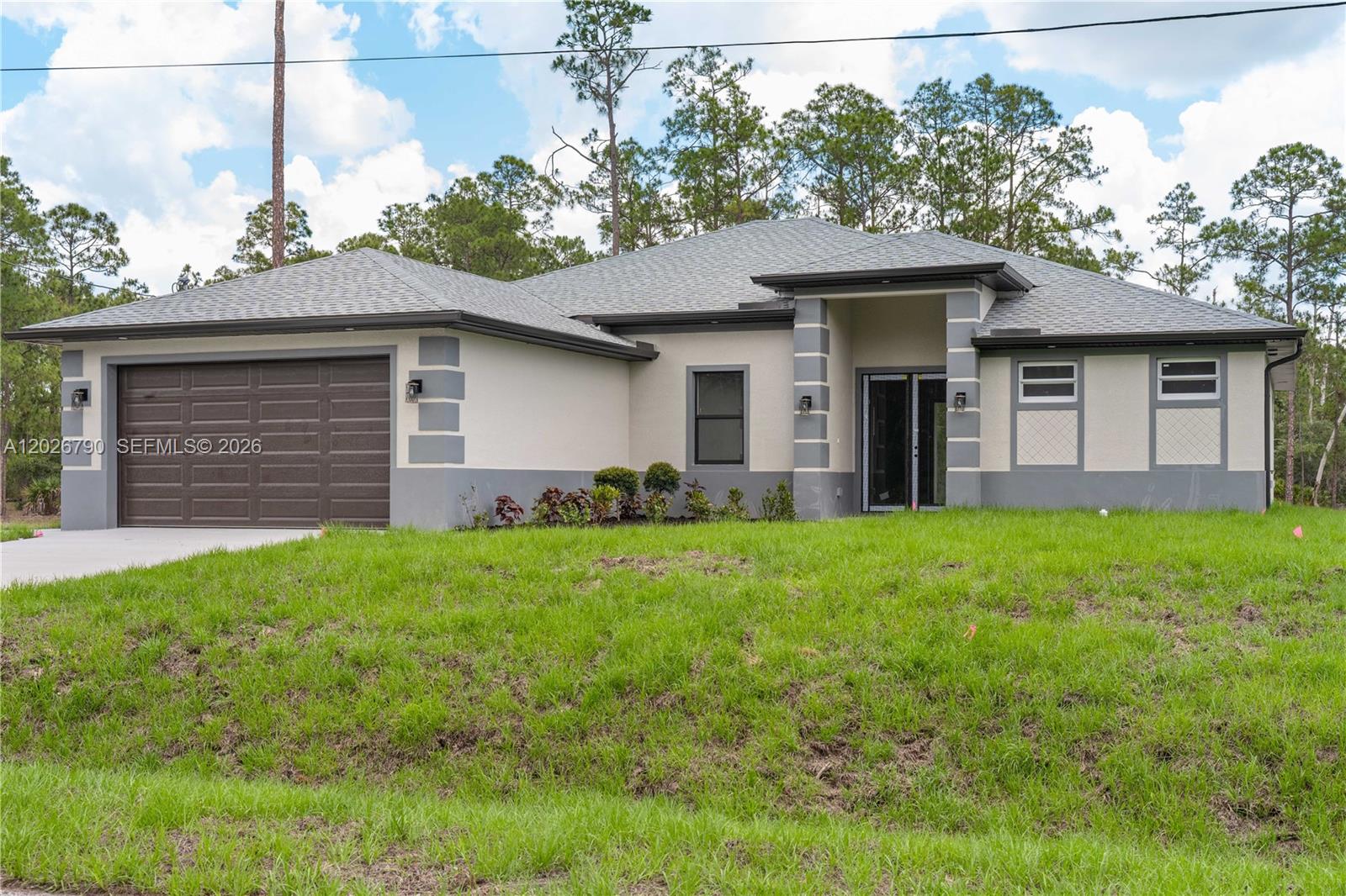 A single-story house with a beige stucco exterior, gray trim, and a two-car garage — 1116 leroy ave, Lehigh Acres FL 33972, LEHIGH ACRES, FL