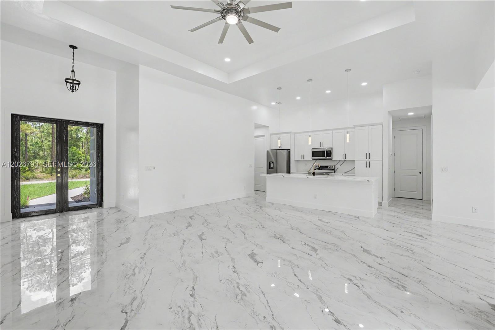 A bright, open-concept kitchen and living area features white cabinetry, marble-patterned tile floors, and recessed lighting — 1116 leroy ave, Lehigh Acres FL 33972, LEHIGH ACRES, FL