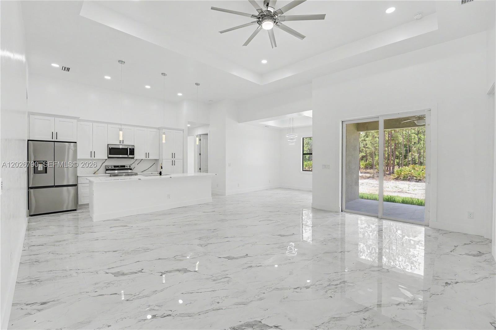 A modern, open-concept kitchen and living area with white cabinetry and polished marble flooring — 1116 leroy ave, Lehigh Acres FL 33972, LEHIGH ACRES, FL