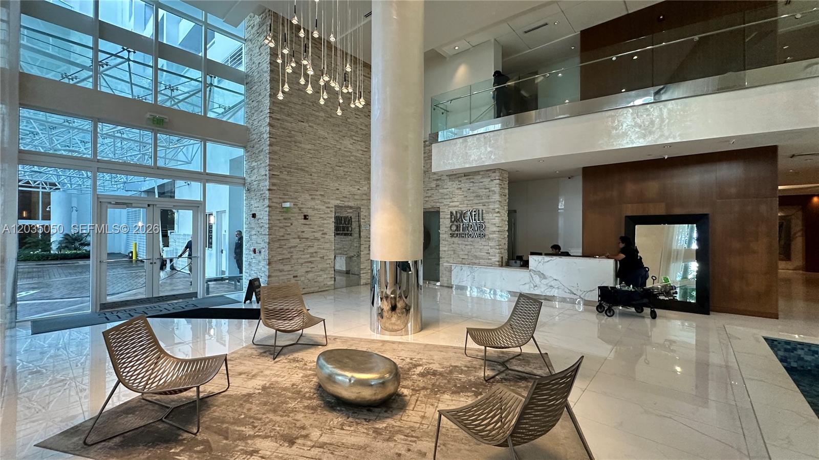 A modern building lobby features a stone accent wall, a large central column, and seating — 41 SE 5th St # 1104, Miami FL 33131, MIAMI, FL
