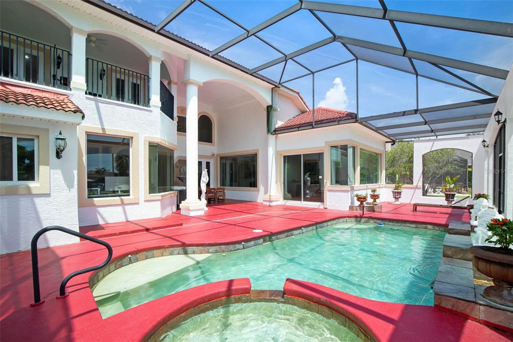 A screened-in patio features a swimming pool, a hot tub, and red painted concrete flooring — 63 FRONT STREET, PALM COAST, FL