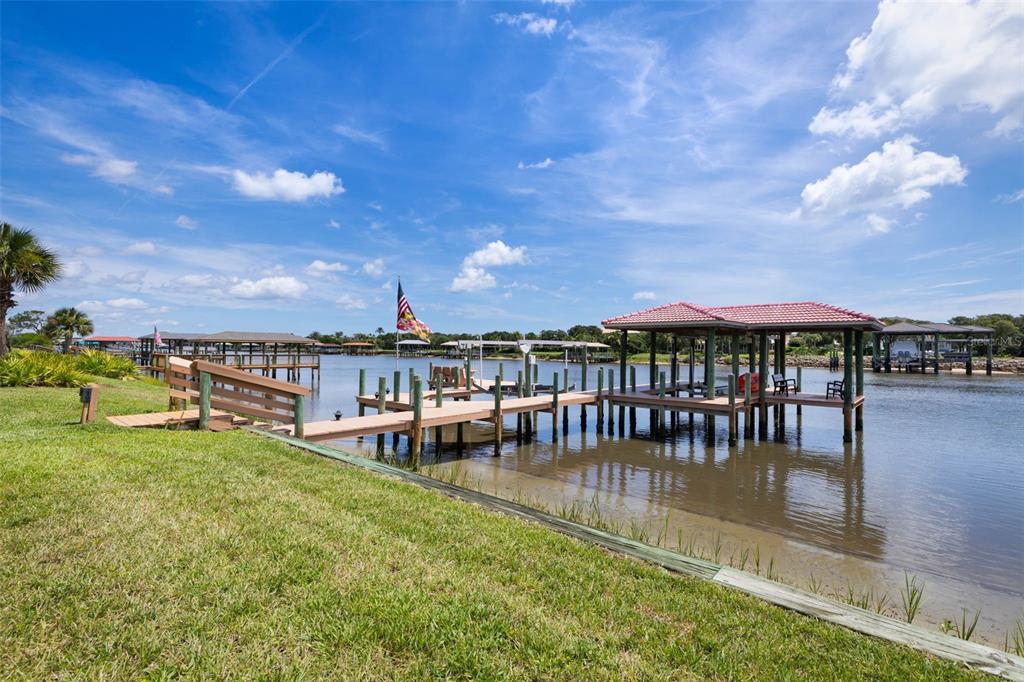 A wooden dock with a covered boat slip extends into a calm canal under blue skies — 63 FRONT STREET, PALM COAST, FL