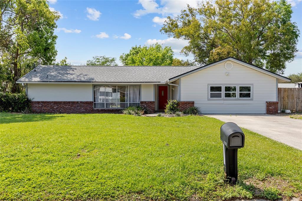 A single-story house with light siding, a brick base, and a red front door — 2130 NE 9TH STREET, OCALA, FL