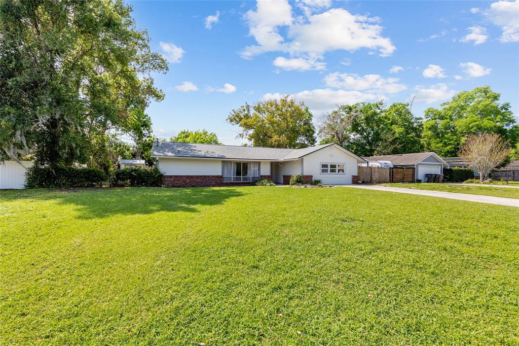 A single-story house with a brick and siding exterior sits behind a large grassy lawn — 2130 NE 9TH STREET, OCALA, FL