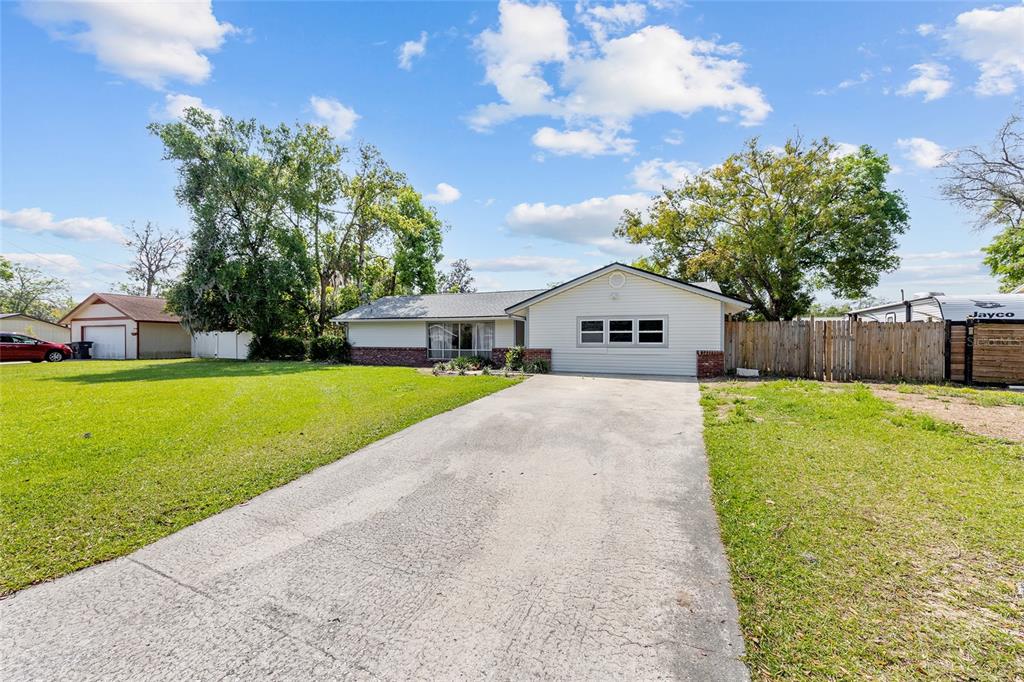 A single-story house with light siding, a concrete driveway, and a large front lawn — 2130 NE 9TH STREET, OCALA, FL