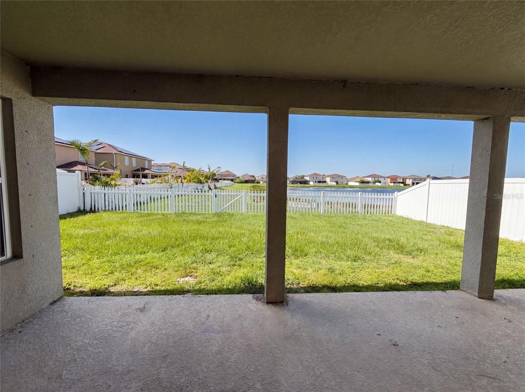 A covered patio overlooks a fenced backyard with a lawn and a distant pond — 11534 BRIGHTON KNOLL LOOP, RIVERVIEW, FL