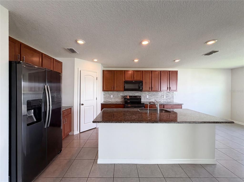 A kitchen features dark wood cabinets, granite countertops, a center island, and stainless steel appliances — 11534 BRIGHTON KNOLL LOOP, RIVERVIEW, FL