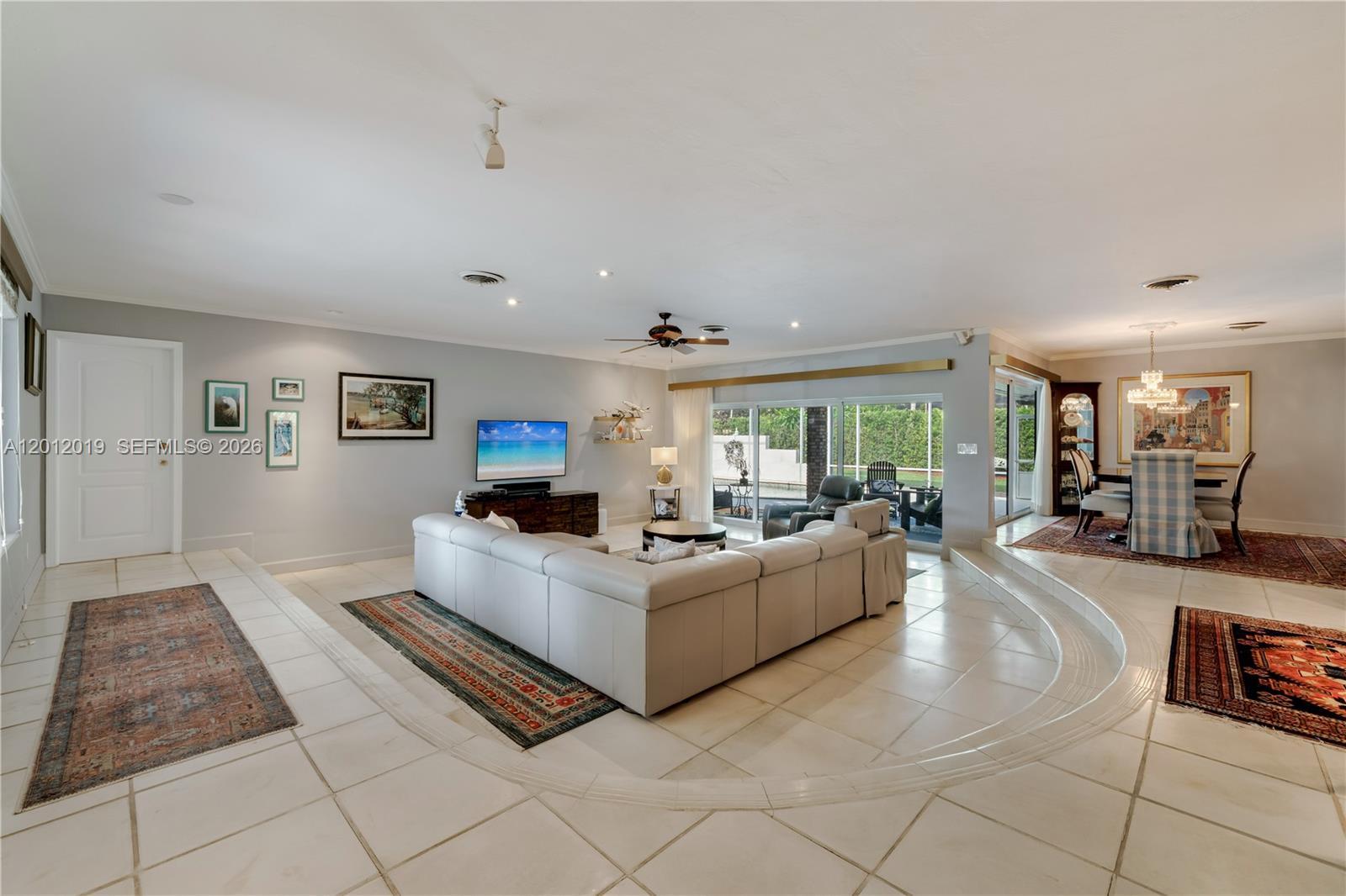 A spacious living room features a sunken seating area, tile flooring, and a dining space — 13401 SW 74th Ave, Pinecrest FL 33156, PINECREST, FL