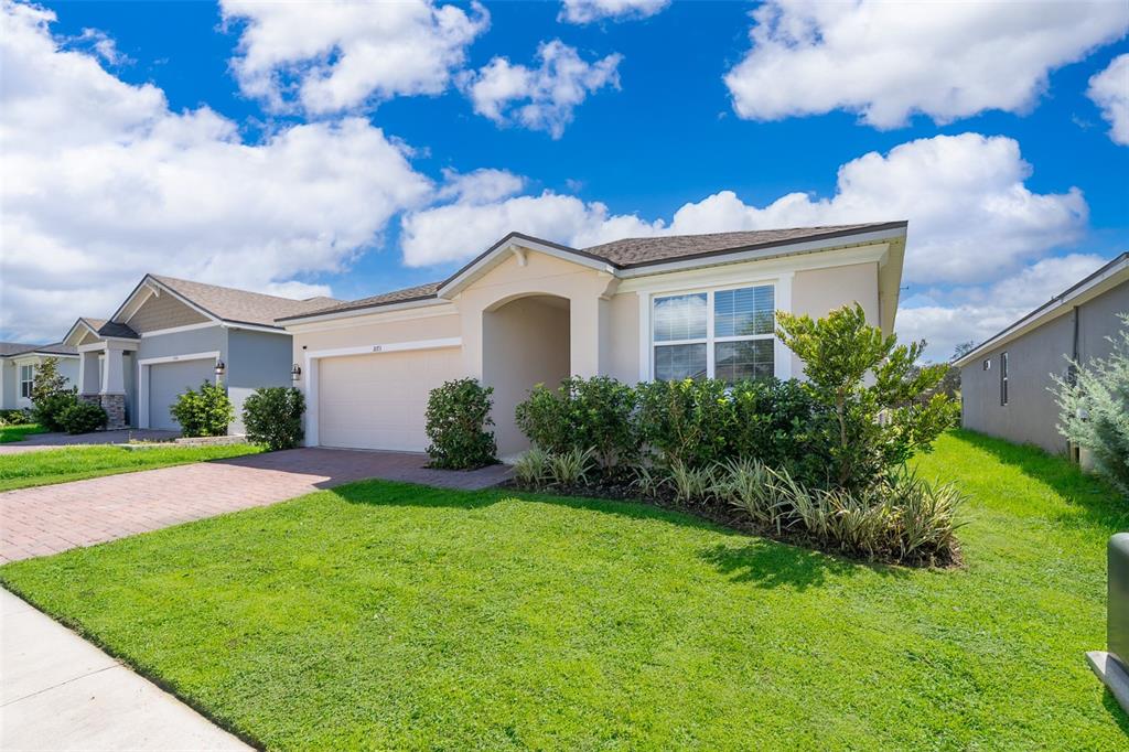 A single-story suburban house with a beige exterior, a two-car garage, and a landscaped yard — 1073 TURQUOISE WAVES COVE, KISSIMMEE, FL