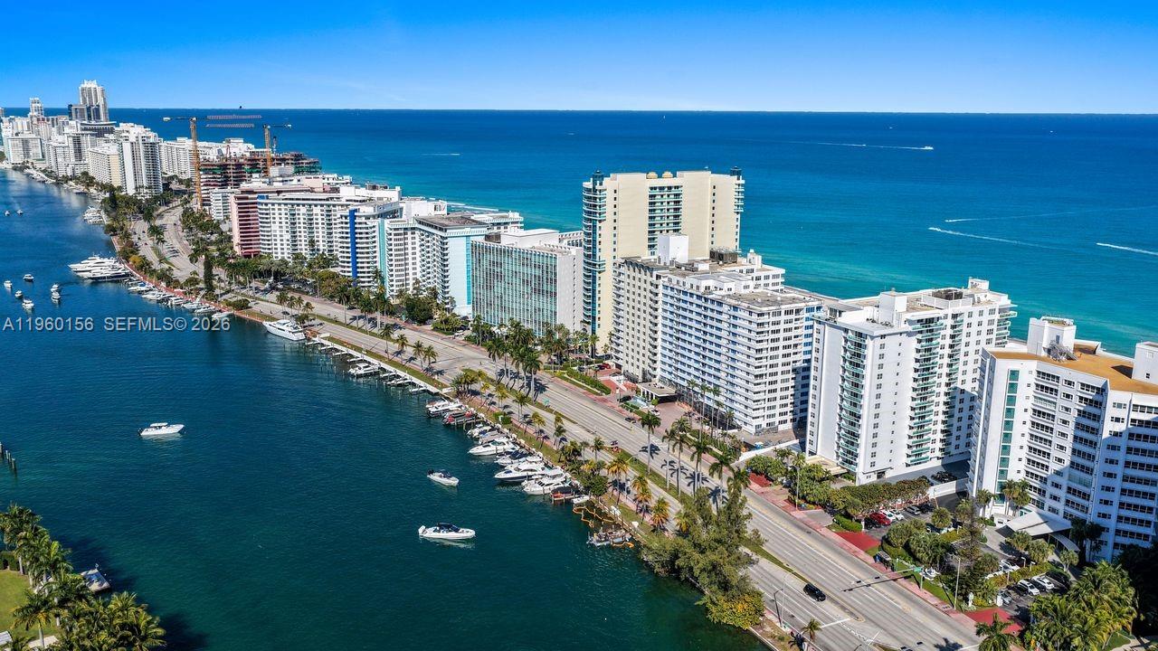 An aerial view shows high-rise buildings along a coastal road next to a boat-filled waterway — 5005 Collins Ave # 504, Miami Beach FL 33140, MIAMI BEACH, FL