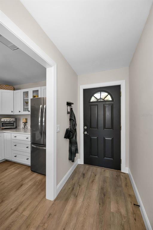 A view of an entryway with a black front door and wood-look flooring — 12025 PROCTOR LOOP UNIT 3, NEW PORT RICHEY, FL