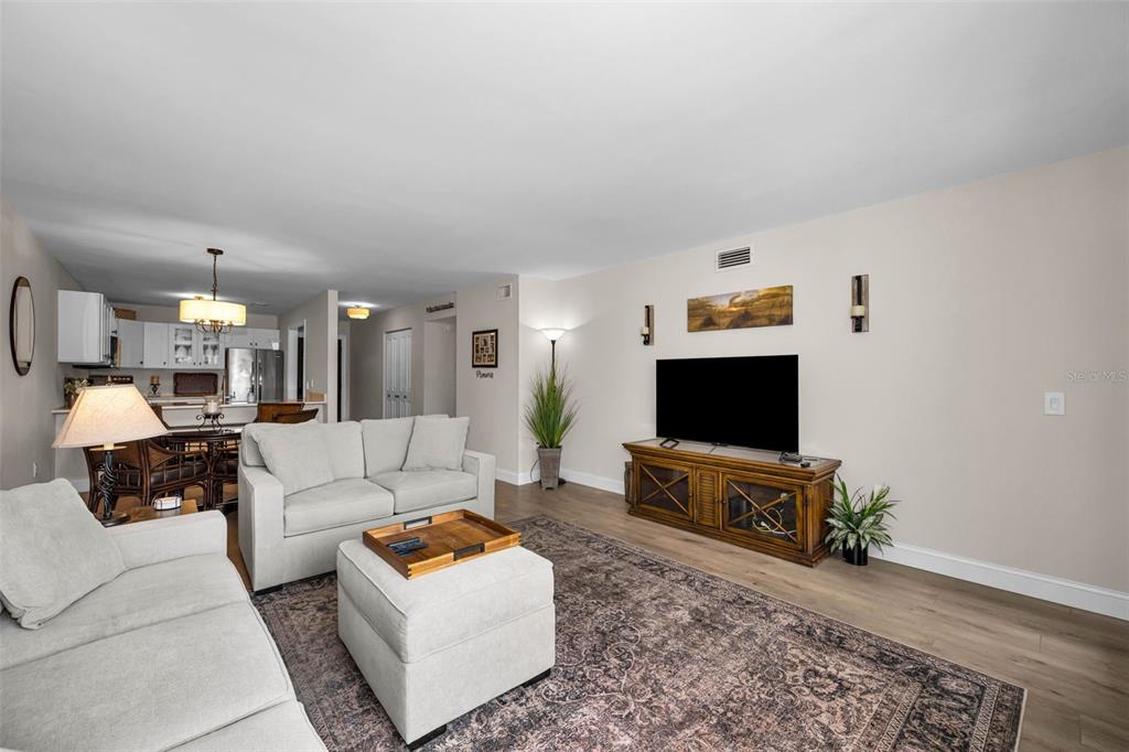 A living room with light-colored sofas, a wooden media console, and an area rug — 12025 PROCTOR LOOP UNIT 3, NEW PORT RICHEY, FL