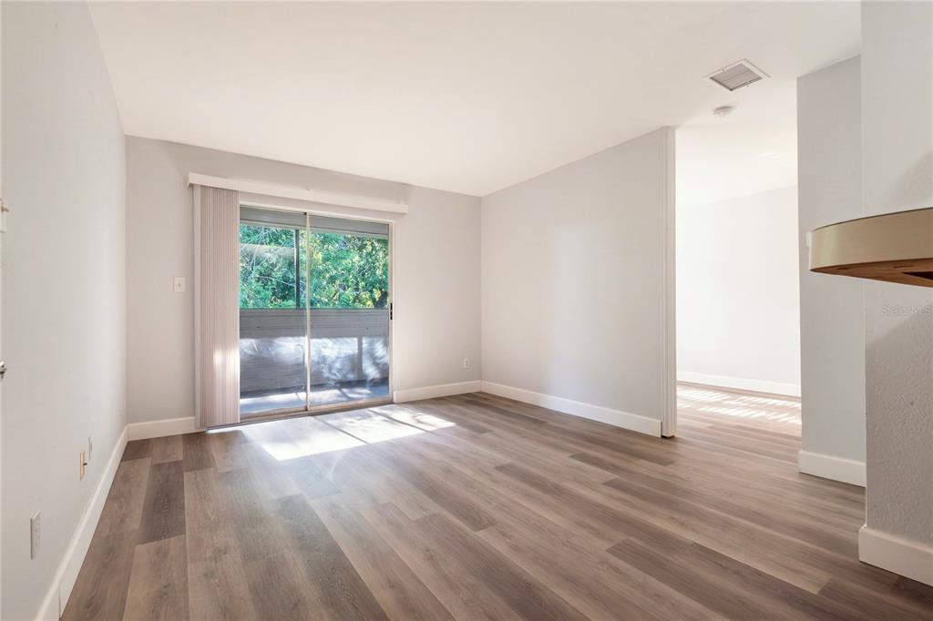 An empty living room features wood-look flooring, light gray walls, and a sliding glass door — 1400 GANDY BOULEVARD N UNIT 1708, ST PETERSBURG, FL