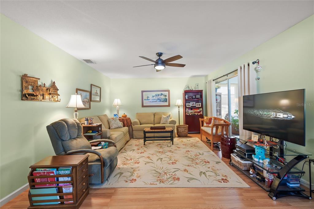 A living room features light green walls, a floral area rug, and a ceiling fan — 1325 GLEN OAKS DRIVE E UNIT 133, SARASOTA, FL
