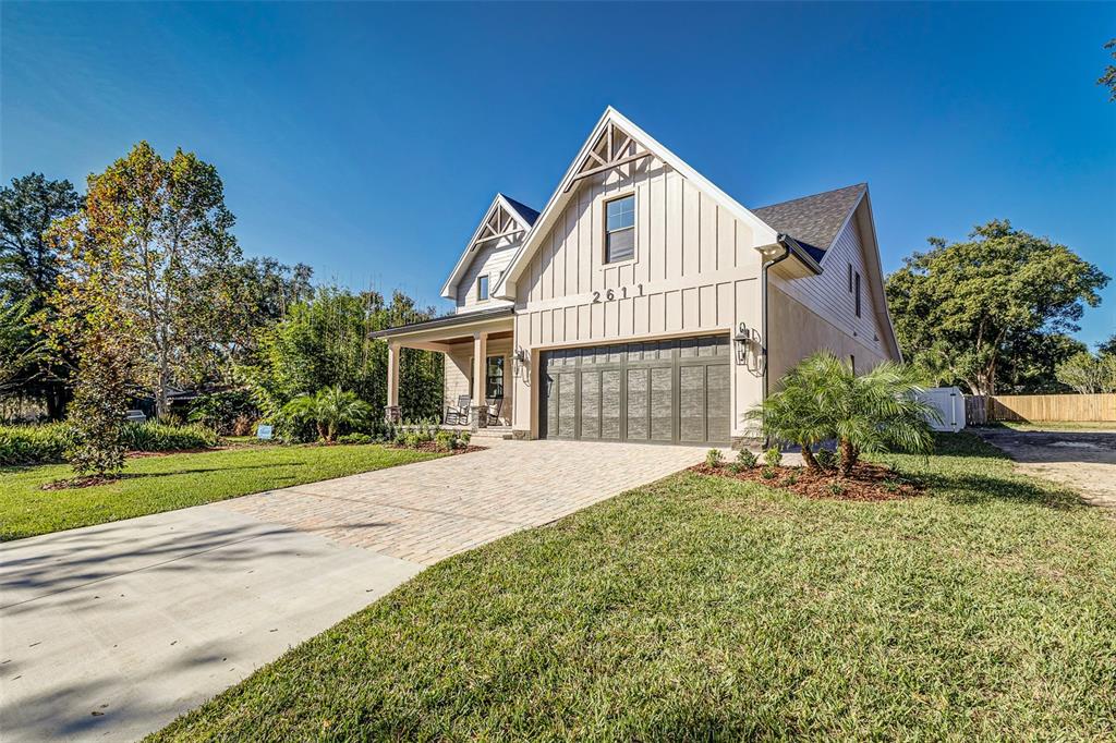 A modern farmhouse with white vertical siding, a dark garage door, and a paved driveway — 2611 BERKELEY AVENUE, LAKELAND, FL