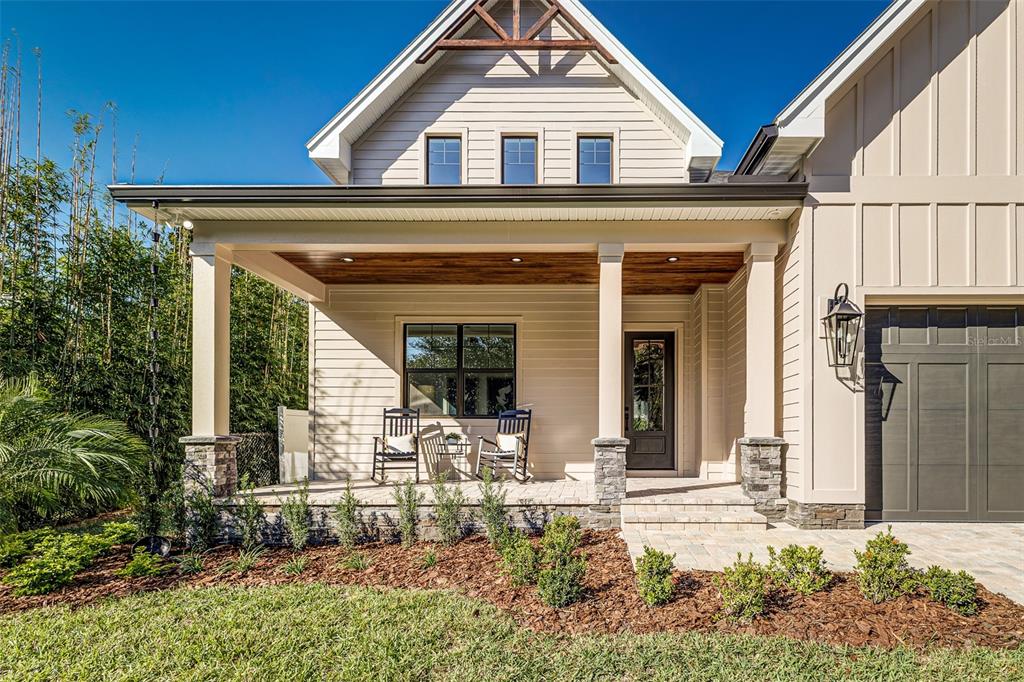 A front porch with stone-based columns, wood ceiling, and two rocking chairs faces a yard — 2611 BERKELEY AVENUE, LAKELAND, FL