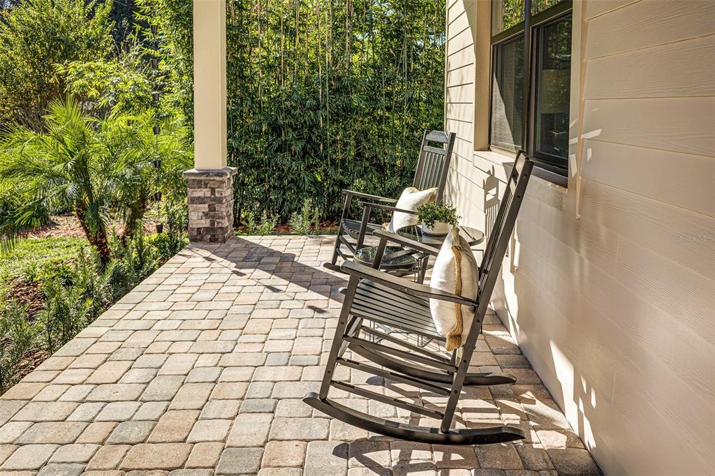 Two black rocking chairs sit on a paved patio next to a house exterior — 2611 BERKELEY AVENUE, LAKELAND, FL