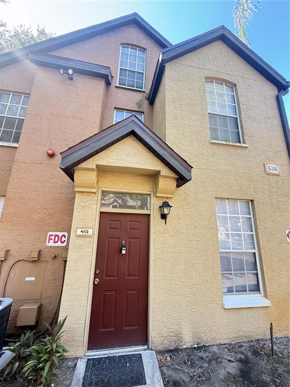 The exterior of a two-story stucco building features a red front door and windows — 6316 RALEIGH STREET UNIT 401, ORLANDO, FL