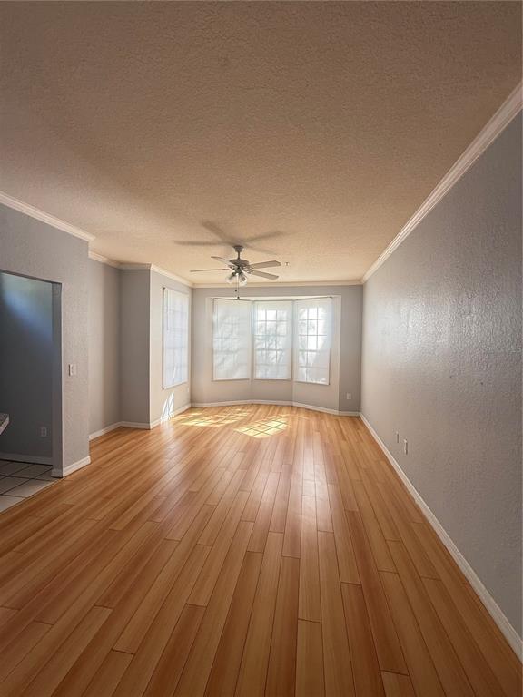 An empty living room features light wood flooring, gray walls, and a bay window — 6316 RALEIGH STREET UNIT 401, ORLANDO, FL