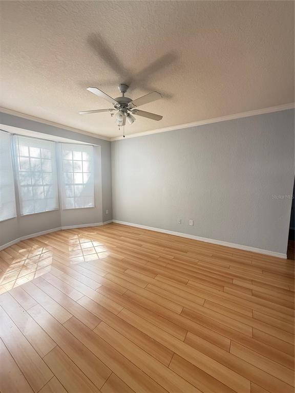 An empty room features light-colored wood flooring, a ceiling fan, and a bay window — 6316 RALEIGH STREET UNIT 401, ORLANDO, FL