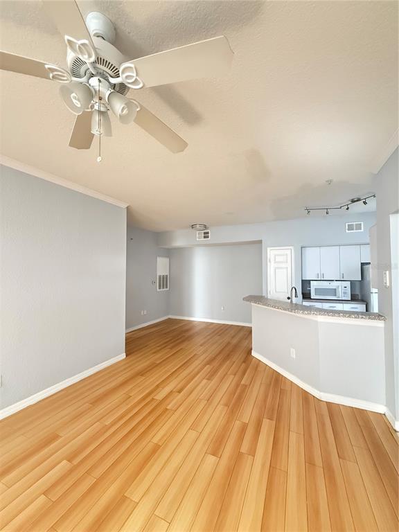 An open-concept living area features light wood flooring, a ceiling fan, and a kitchen counter — 6316 RALEIGH STREET UNIT 401, ORLANDO, FL