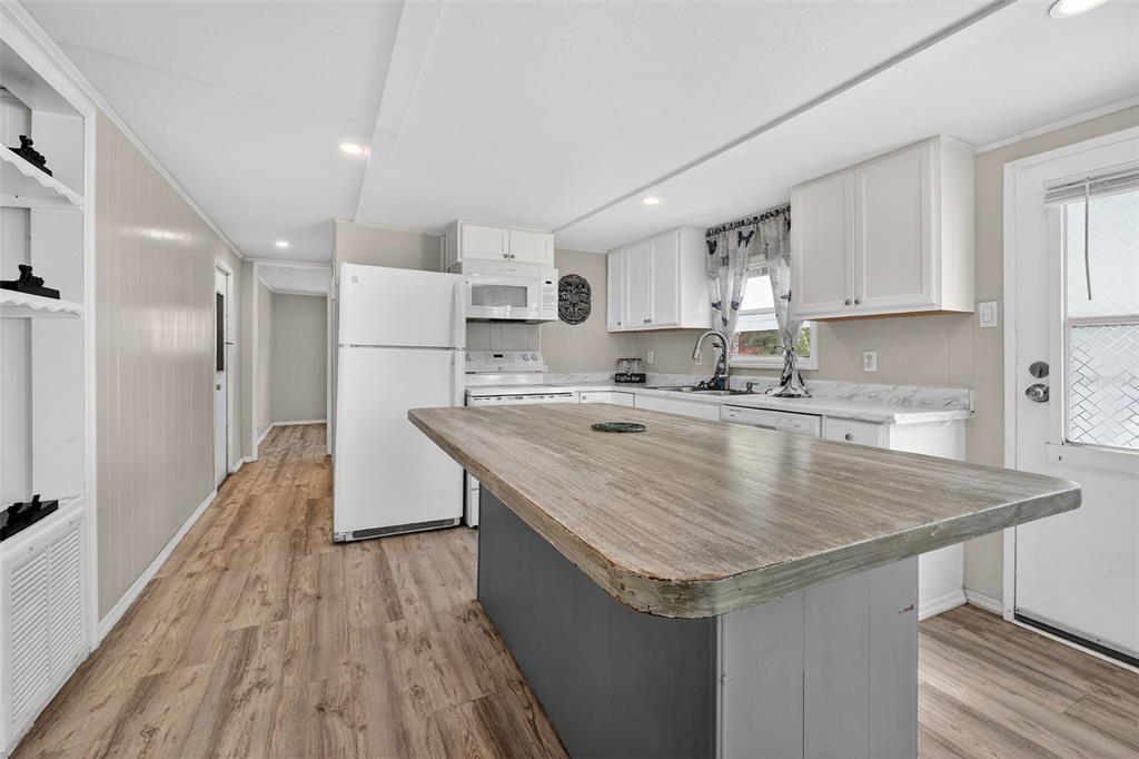 A kitchen features a large wooden island, white cabinets, and light wood-look flooring — 5413 ISABELLE AVENUE, PORT ORANGE, FL