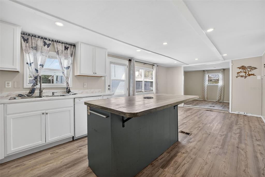 A kitchen features white cabinets, a dark gray island with a wood top, and flooring — 5413 ISABELLE AVENUE, PORT ORANGE, FL