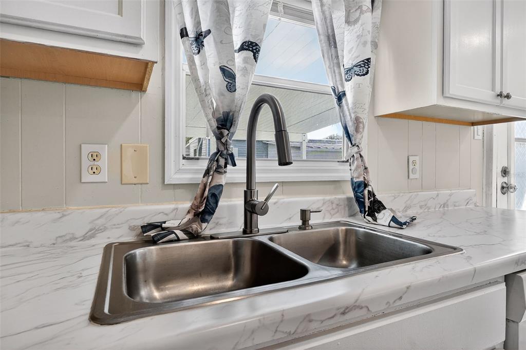 A kitchen sink with a dark metal faucet sits in a white marble-patterned countertop — 5413 ISABELLE AVENUE, PORT ORANGE, FL