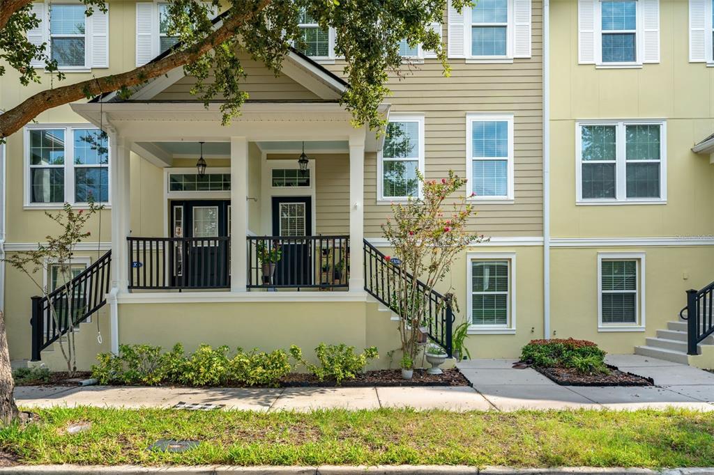 A multi-story townhouse exterior features a covered front porch, black railings, and light-colored siding — 1380 MILL STREAM LANE, WINTER SPRINGS, FL