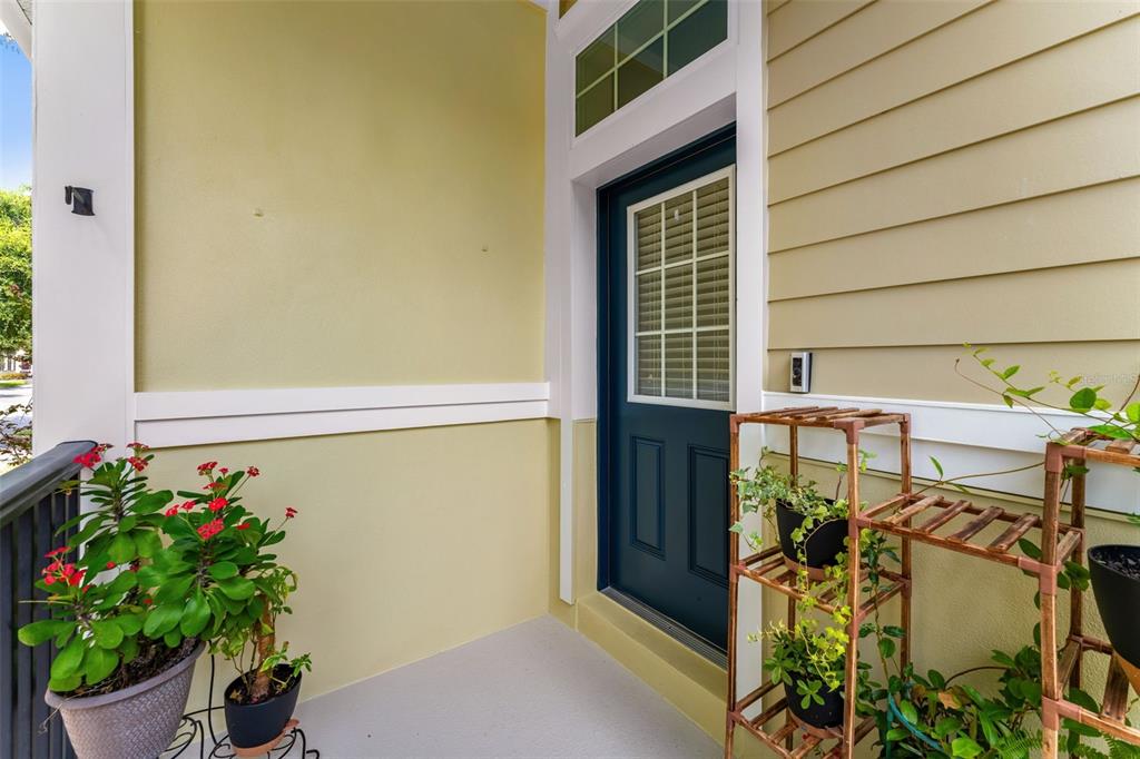 A covered porch features a dark blue door, light yellow walls, and several potted plants — 1380 MILL STREAM LANE, WINTER SPRINGS, FL