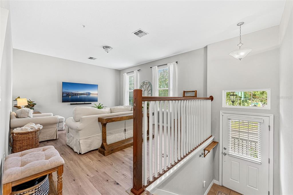 A living room with light wood floors, white sofas, and a wooden staircase railing — 1380 MILL STREAM LANE, WINTER SPRINGS, FL