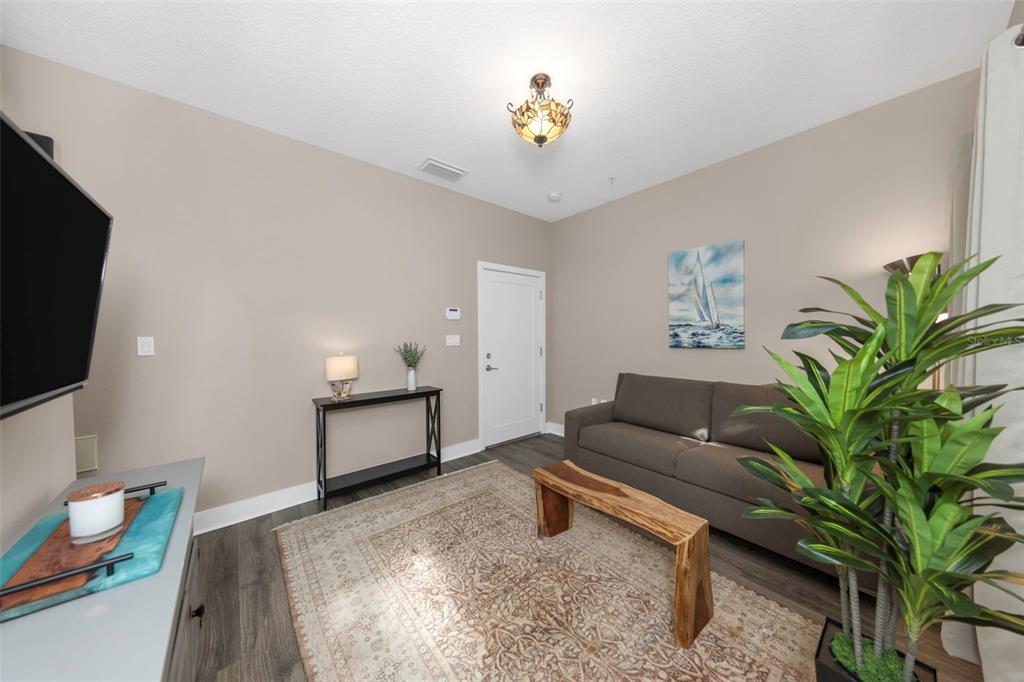 A living room features a brown sofa, a wooden bench, and a patterned area rug — 946 HIGHLAND AVENUE UNIT 45, DUNEDIN, FL