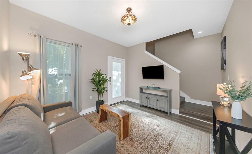 A living room features a gray sofa, a wood coffee table, and stairs leading upward — 946 HIGHLAND AVENUE UNIT 45, DUNEDIN, FL