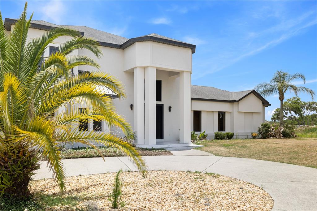 A two-story white house with a palm tree in the foreground and a circular driveway — 10640 LAKE MINNEOLA SHORES, CLERMONT, FL