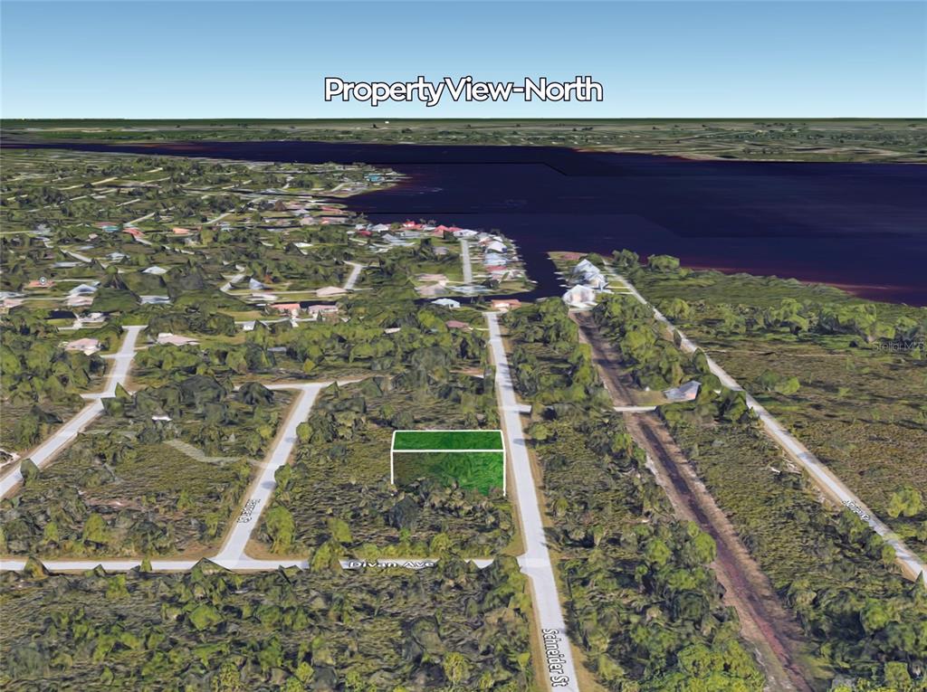 An aerial view shows a vacant, rectangular lot highlighted in green near a waterfront area — 4387 SCHNEIDER STREET, PORT CHARLOTTE, FL