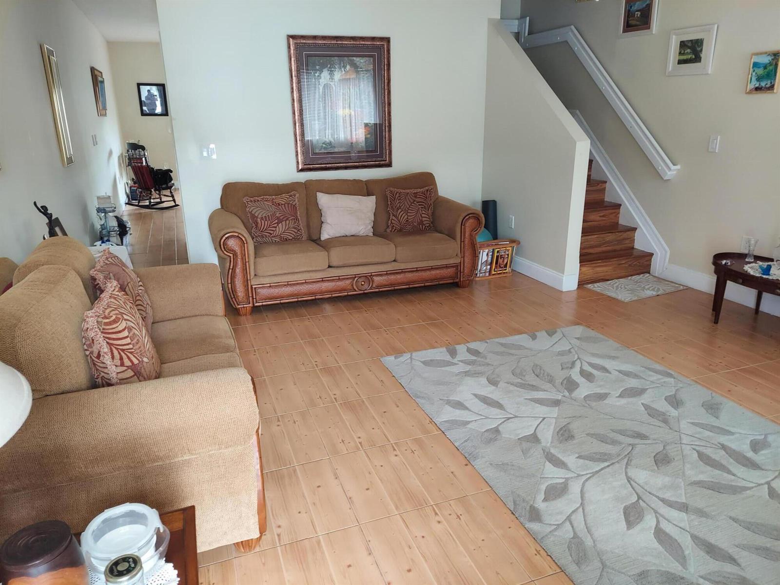 A living room features two brown sofas, a patterned area rug, and wooden stairs — 2208 SE 24th Place, Homestead FL 33035, HOMESTEAD, FL