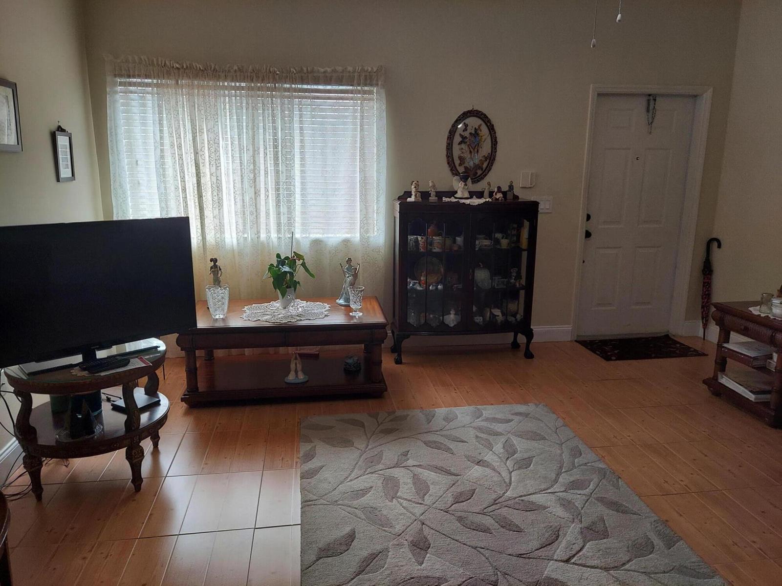 A living room features light wood flooring, a large area rug, and a wooden display cabinet — 2208 SE 24th Place, Homestead FL 33035, HOMESTEAD, FL