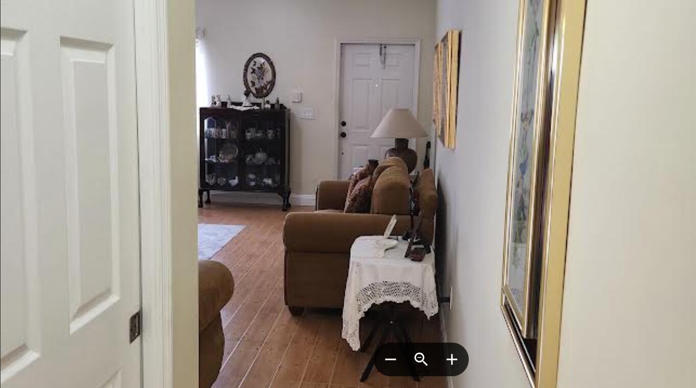 A view from a doorway into a living room with wood flooring and a sofa — 2208 SE 24th Place, Homestead FL 33035, HOMESTEAD, FL