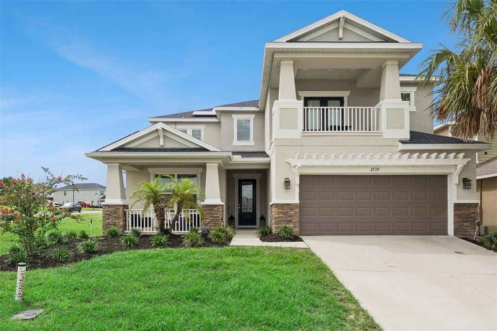A two-story suburban house with a tan stucco exterior, stone accents, and a two-car garage — 2739 PLUME ROAD, CLERMONT, FL