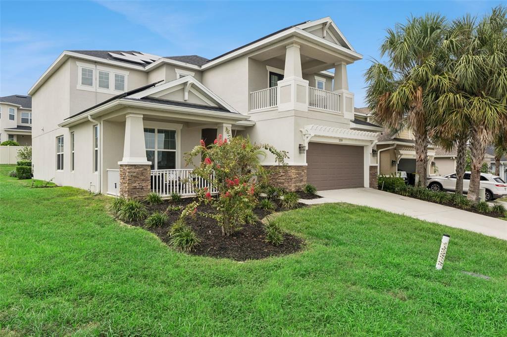 A two-story suburban house with a tan stucco exterior, stone accents, and a front porch — 2739 PLUME ROAD, CLERMONT, FL