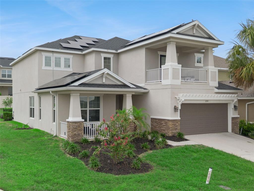 A two-story suburban house with a tan stucco exterior, stone accents, and a front porch — 2739 PLUME ROAD, CLERMONT, FL