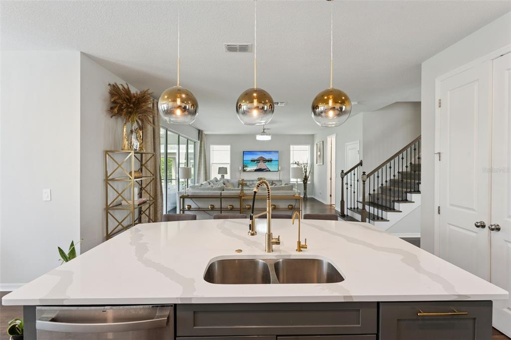 A kitchen island with a white quartz countertop and gold faucet overlooks a living room — 2739 PLUME ROAD, CLERMONT, FL