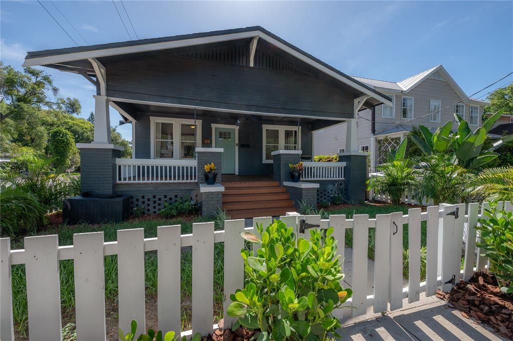 A dark gray bungalow with a front porch, white picket fence, and light blue door — 2831 N MORGAN STREET, TAMPA, FL
