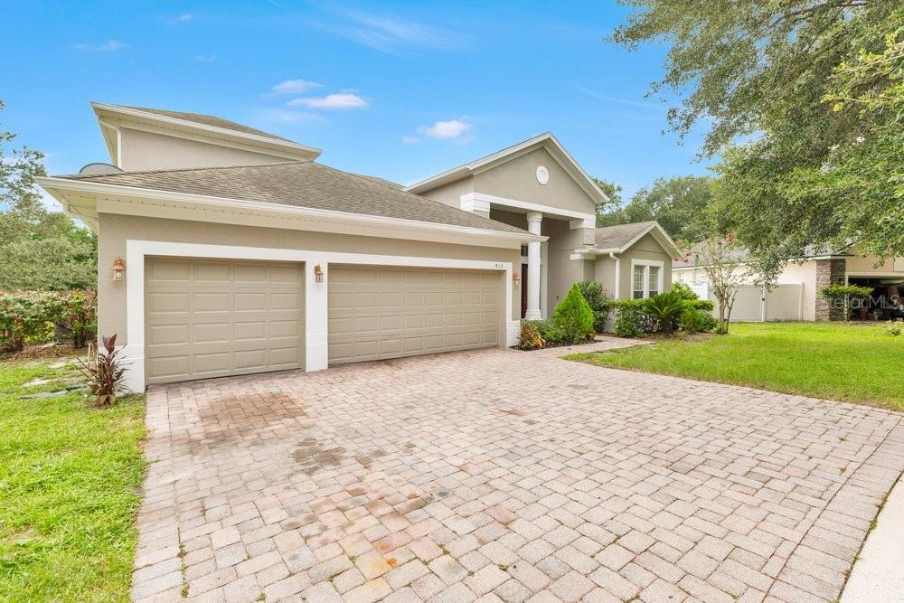 A tan house with a two-car garage and a paved driveway under a blue sky — 912 HIRE CIRCLE, OCOEE, FL