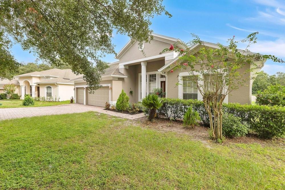 A tan single-story house with a two-car garage and a front porch under a tree — 912 HIRE CIRCLE, OCOEE, FL