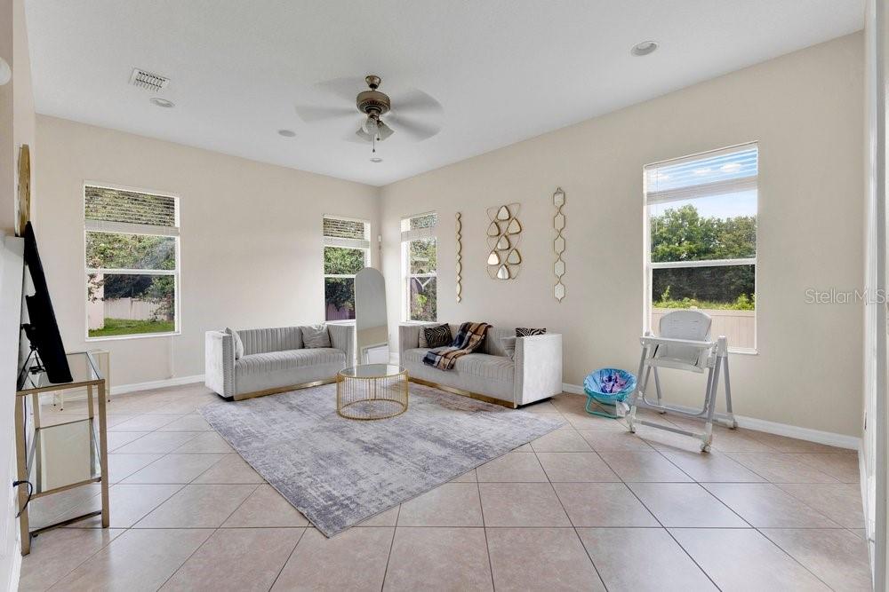 A living room features light tile floors, two grey sofas, a coffee table, and large windows — 912 HIRE CIRCLE, OCOEE, FL