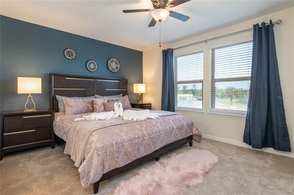 A bedroom features a dark blue accent wall, a wooden bed frame, and two windows — 8931 ZURICH LANE, KISSIMMEE, FL